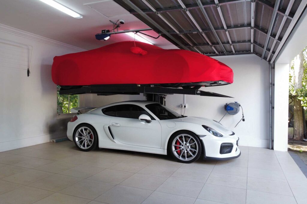 Two cars parked in a single garage at home using a parking lift